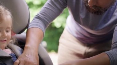 Babanın çocuğu bebek koltuğuna oturttuğu videoyu kapat. 8K 'da kırmızı helyum kamerayla çekildi..