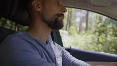 Yakışıklı bir adamın araba sürüşünün videosunu eğ. 8K 'da kırmızı helyum kamerayla çekildi..