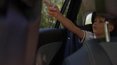 Arabanın camından bir şeyi gösteren bir çocuk videosu. 8K 'da kırmızı helyum kamerayla çekildi..