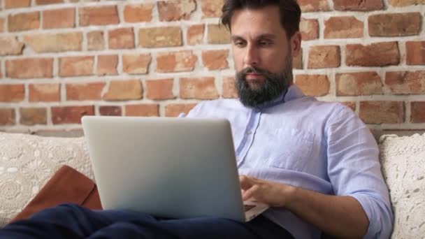 셔츠를 앉아서 노트북을 사용하는 남자의 비디오 카메라로 — 비디오