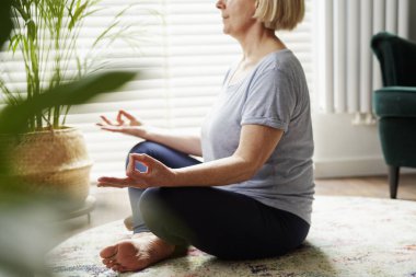 Evde meditasyon yapan yaşlı kadın görüntüsü