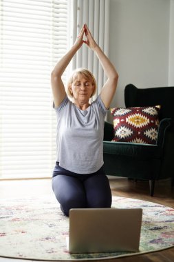 Aktif kıdemli kadın evde meditasyon yapıyor.