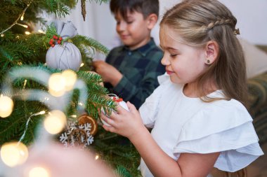 Noel ağacını birlikte süsleyen kardeş. 