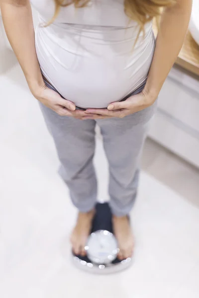 Těhotná žena ovládá její váha — Stock fotografie