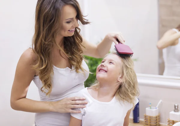 Mother brushes daughter's hair — Stock Photo, Image