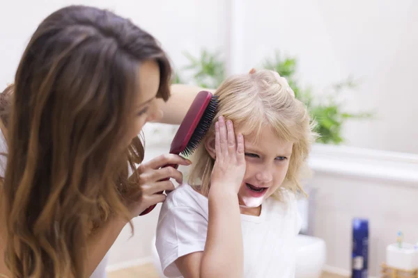 Mother brushes daughter's hair — Stock Photo, Image