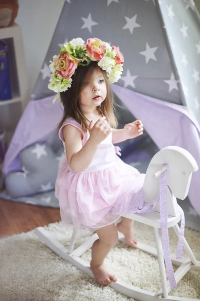 Bébé fille en couronne florale sur jouet de cheval — Photo