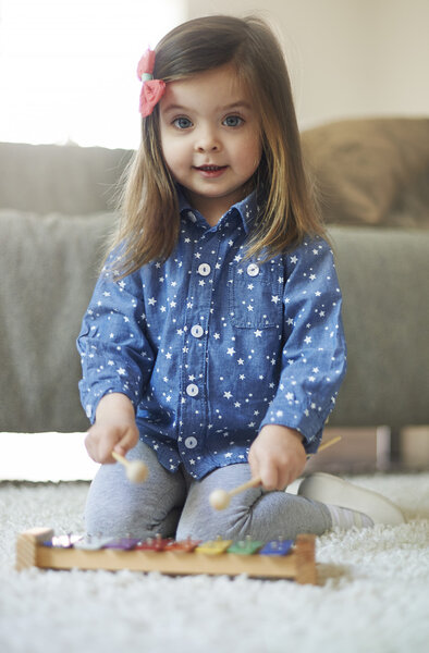 little girl is playing on xylophone