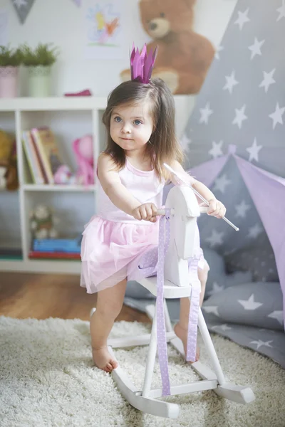 Baby flicka i klänning på häst leksak. — Stockfoto