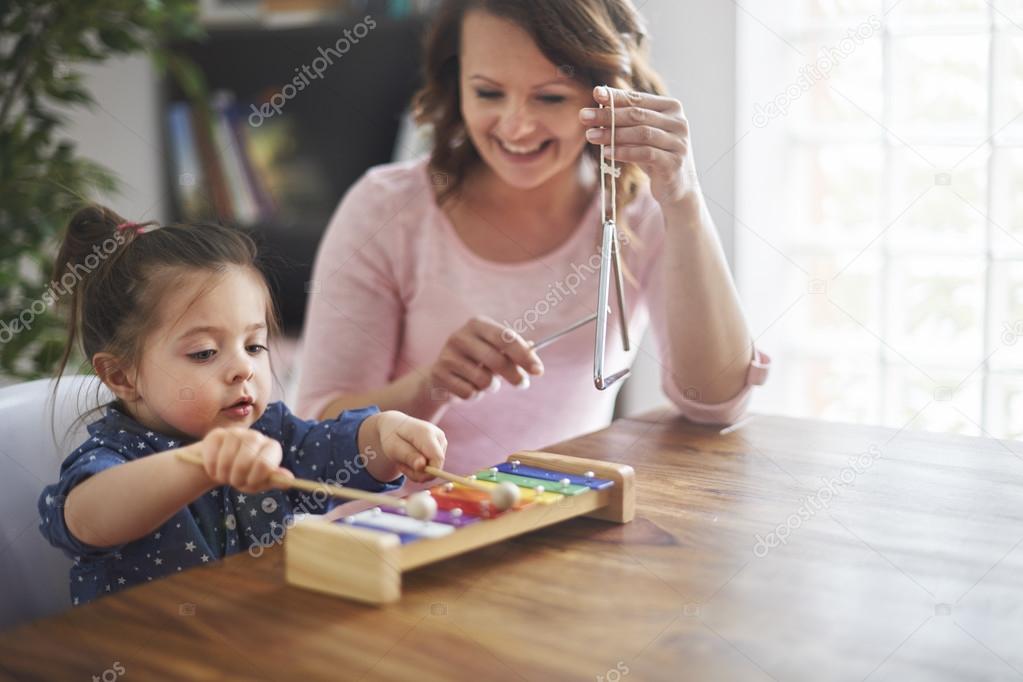 Mother and her daughter play on musical instrument