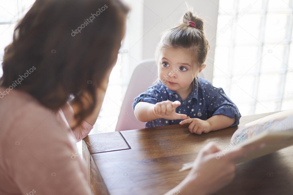 Cute girl with mom reading a book