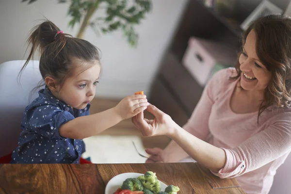 Mother gives carrot to her child — Stock Photo, Image