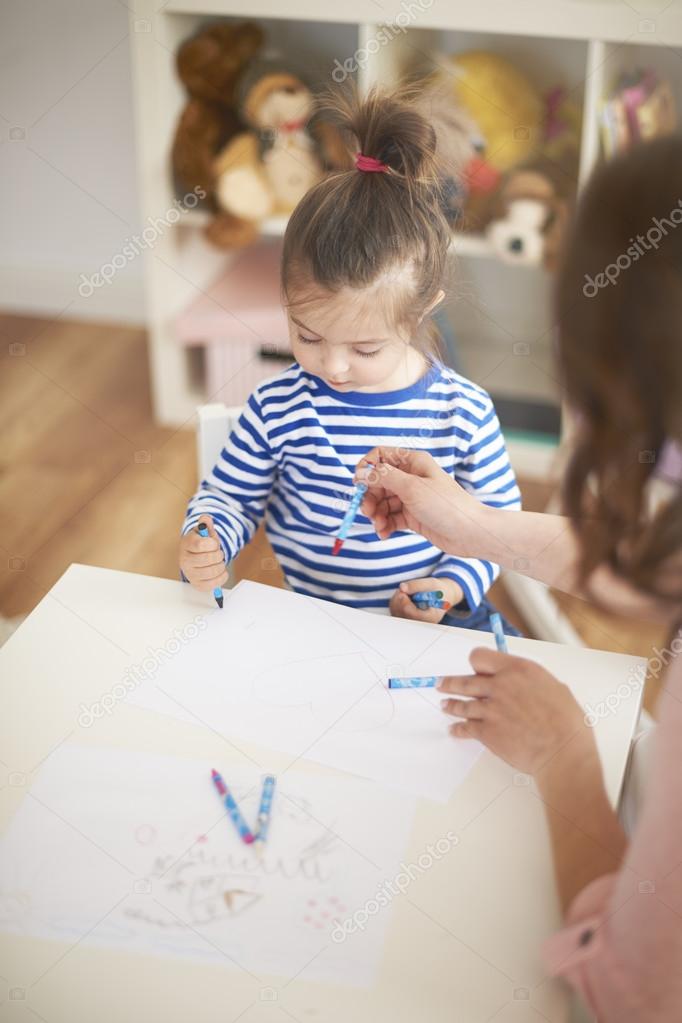 Cute girl drawing picture with her mom