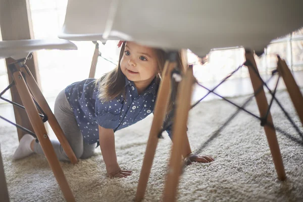 Скрытая маленькая девочка под столом — стоковое фото