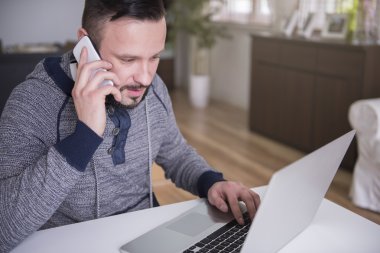 Cep telefonu ve dizüstü bilgisayar kullanan adam