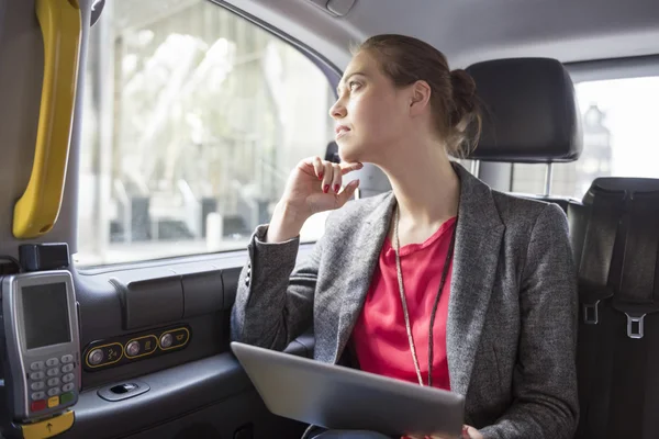 Successful businesswoman in cab wit tablet — Stockfoto