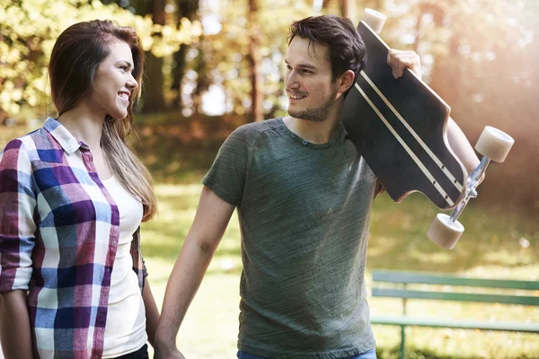 Pareja enamorada caminando en parque con patín — Foto de Stock