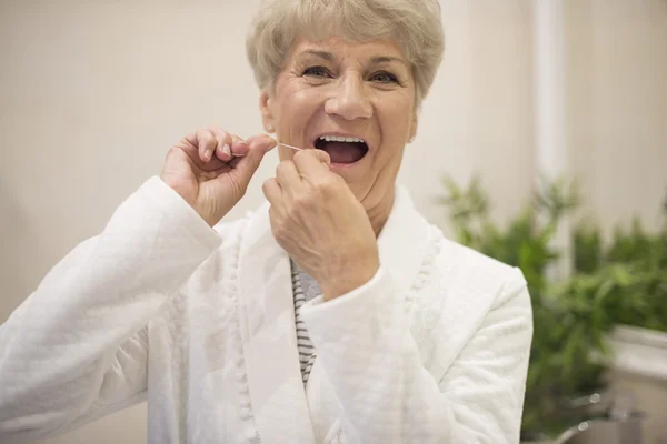 Mature woman with dental floss — Stock Photo, Image