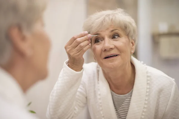 Reife Frau beim Pinseln der Augenbrauen — Stockfoto