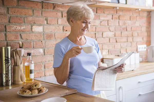 Woman drinking tea and reading paper — Stock Photo, Image