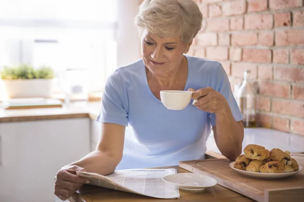 Kvinne som drikker te og leser papir – stockfoto