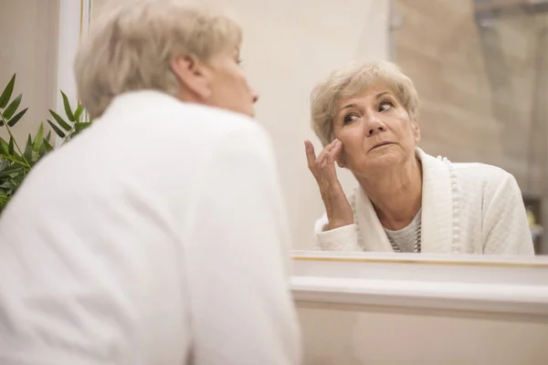 Volwassen vrouw op zoek in spiegel — Stockfoto