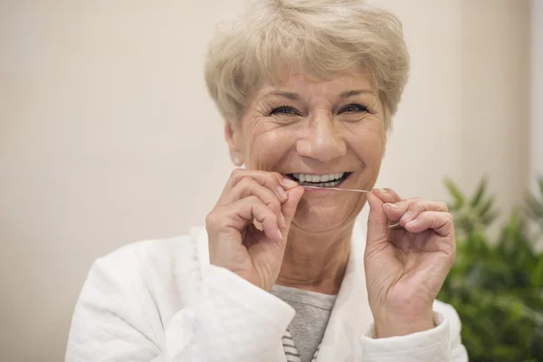 Mature woman with dental floss — Stock Photo, Image