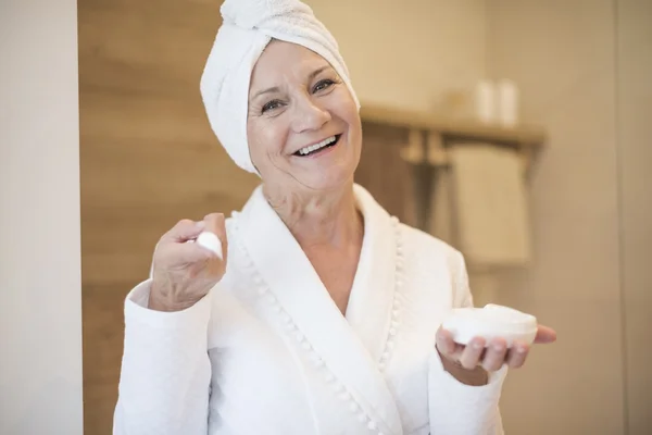 Senior woman moisturizing her face — Stock Photo, Image