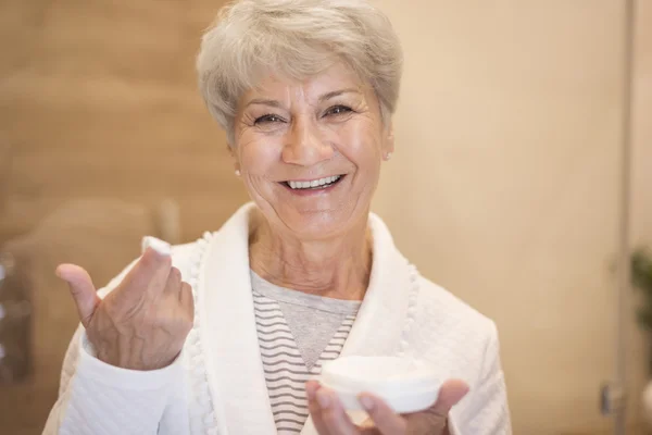 Seniorin benutzt Feuchtigkeitscreme — Stockfoto