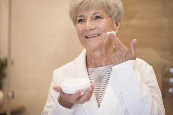 Volwassen vrouw met behulp van anti age cream — Stockfoto