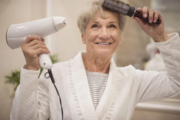 Зрелая женщина сушит волосы — стоковое фото