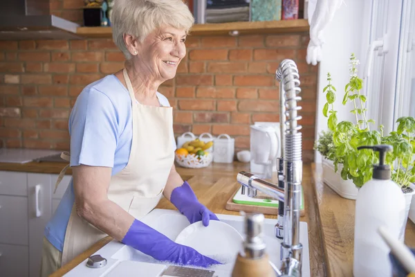 Volwassen vrouw wassen platen in keuken — Stockfoto