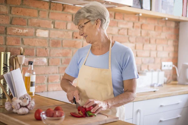 Reife Frau bereitet schmackhaftes Essen zu — Stockfoto