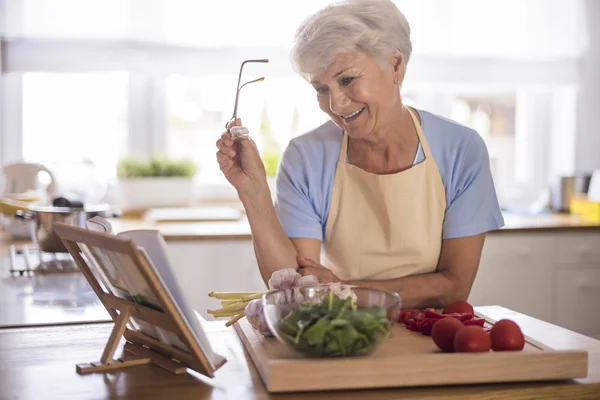 Mature woman looking to recipe book — Stock Photo, Image