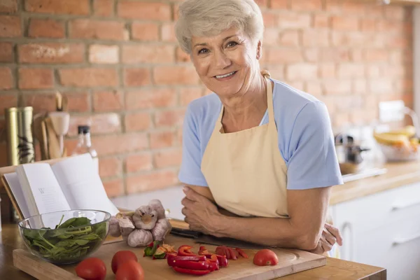 Reife Frau bereitet schmackhaftes Essen zu — Stockfoto