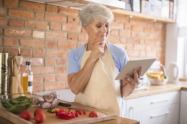 Mature woman looking recipe on tablet — Stock Photo, Image