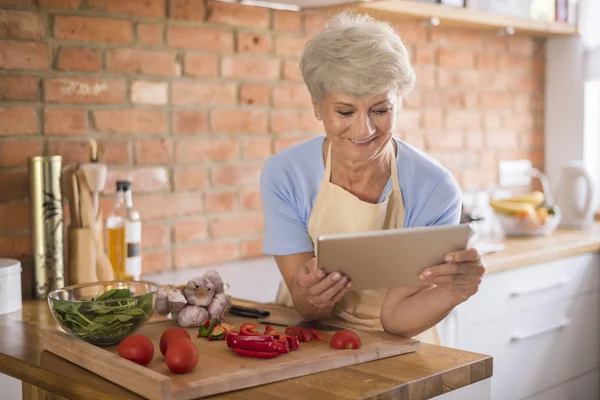 Mature woman looking recipe on tablet — Stock Photo, Image