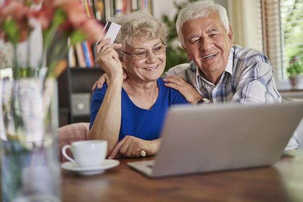 Happy mature couple with laptop and credit card — Stock Photo, Image