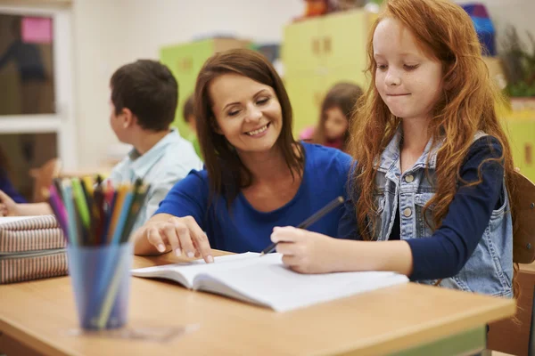 Учитель помогает девочке писать уроки — стоковое фото