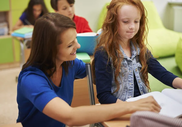 Teacher helping her pupil with her homework — Stock Photo, Image