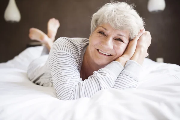 Mature woman smiling in bed — Stock Photo, Image