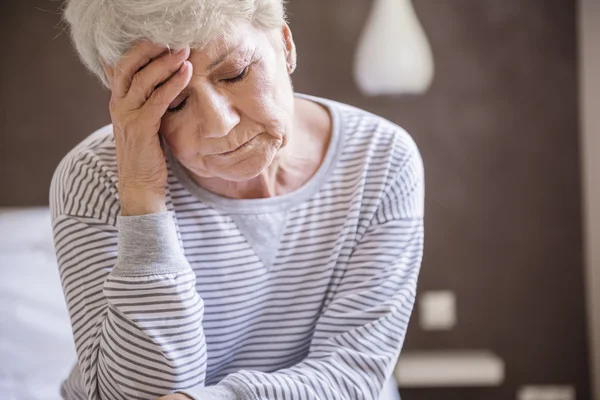 Зрелая женщина в постели с головной болью — стоковое фото