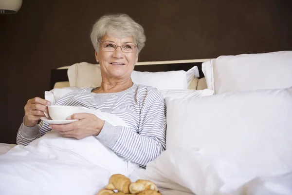 Volwassen vrouw in bed met voedsel — Stockfoto