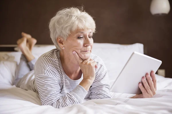 Mujer madura con portátil en la cama — Foto de Stock