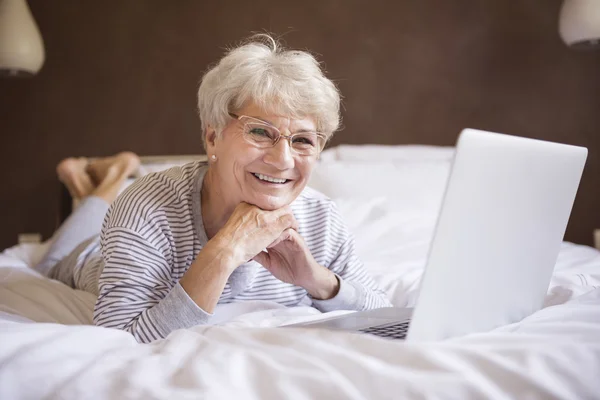 Mature woman with laptop in bed — Stock Photo, Image