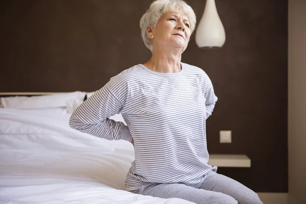 Reife Frau sitzt auf Bett — Stockfoto