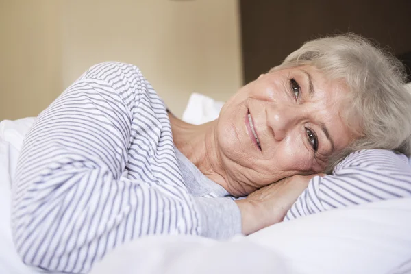 Reife Frau im Bett tagträumend — Stockfoto