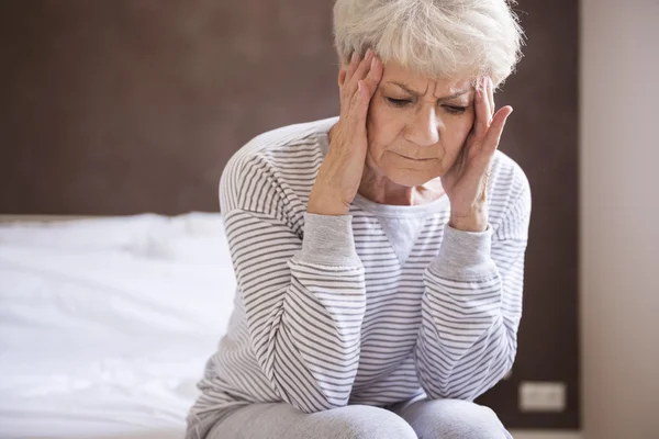 Mujer madura en la cama con dolor de cabeza — Foto de Stock