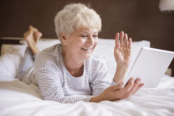 Donna matura con computer portatile a letto — Foto Stock