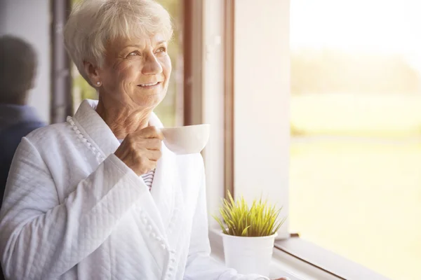 Femme mature avec thé près de la fenêtre — Photo